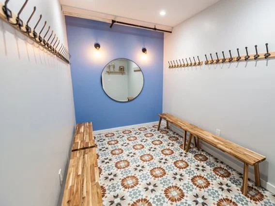 PtrBlt Miami Yoga Garage renovation photo of changing room with statement floor tiles, wood benches and a periwinkle blue wall